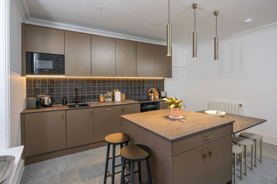Contemporary kitchen with integral appliances, a central island and fitted breakfast bar