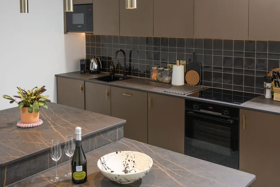 Contemporary kitchen with integral appliances, a central island and fitted breakfast bar