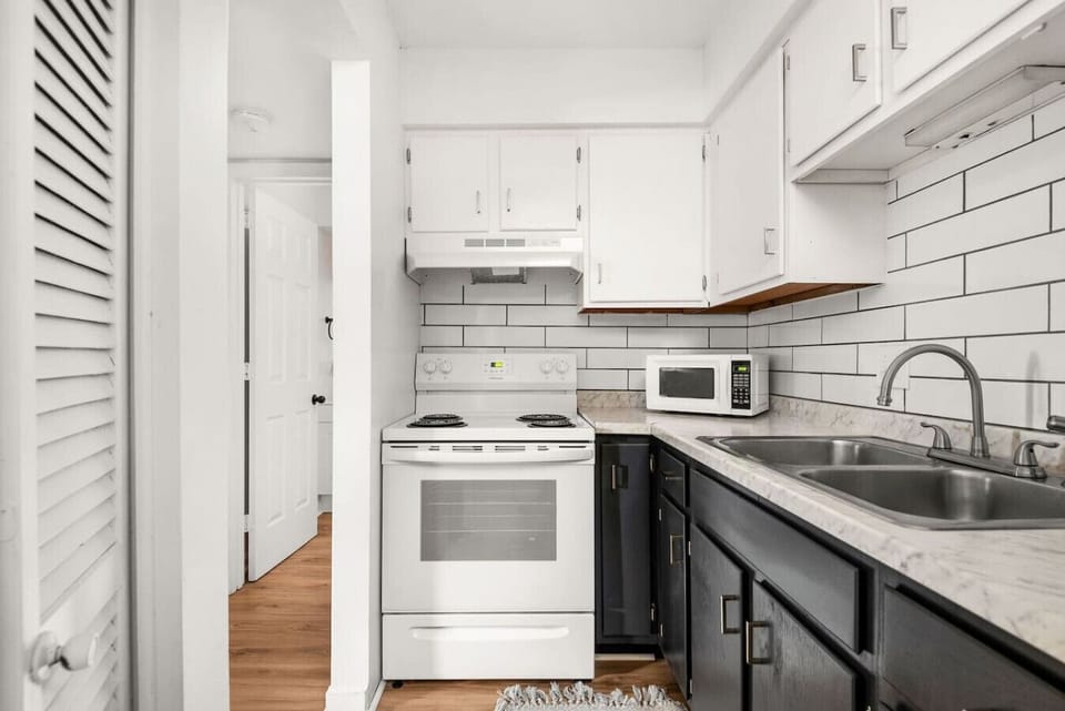 The bathroom features crisp white subway tile and a clean minimalist aesthetic.