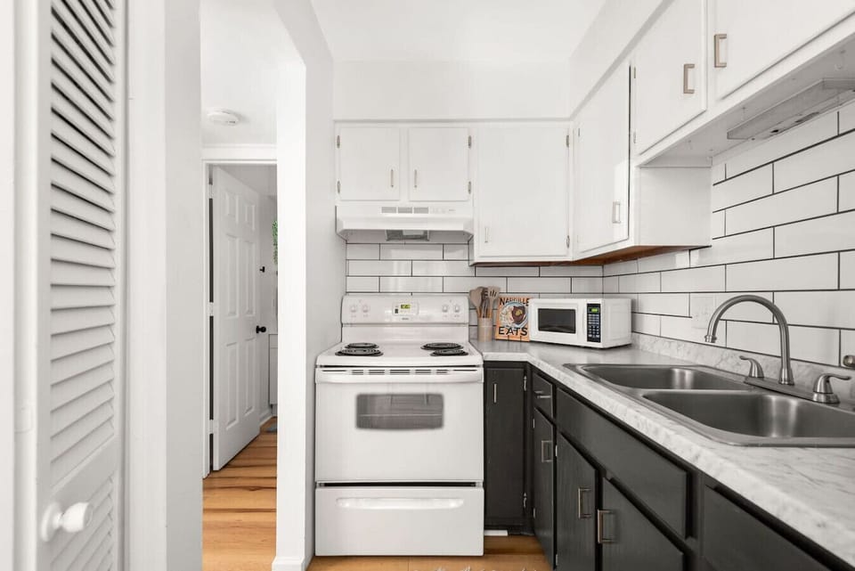 White upper cabinets and dark lowers give the kitchen a sleek and modern look.