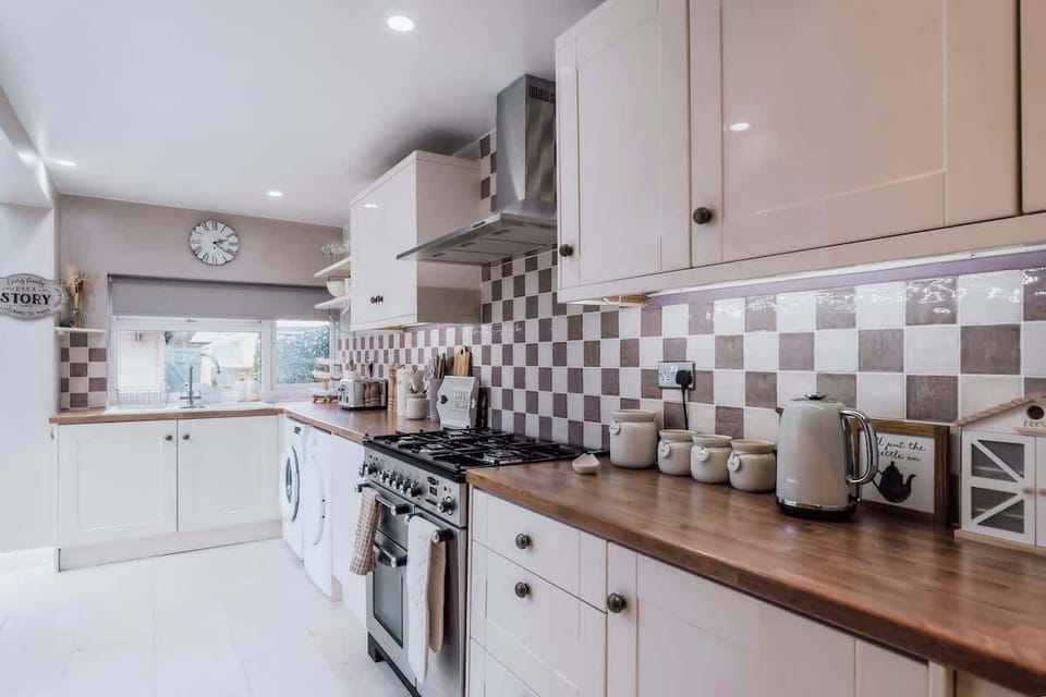 Detailed kitchen counter with stove, tiles, jars, and organized essentials.

