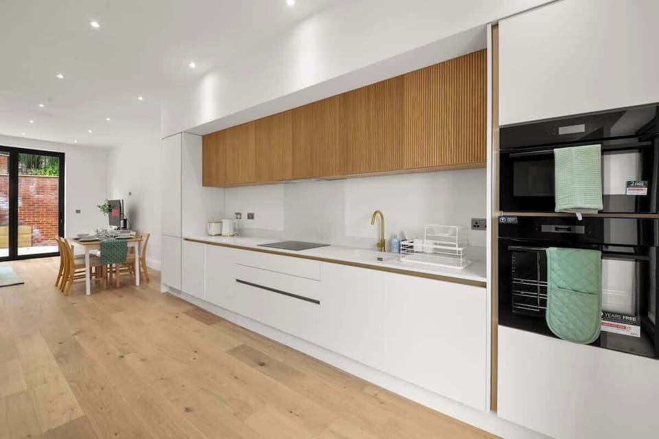 Sleek contemporary kitchen with wooden accents and integrated appliances design
