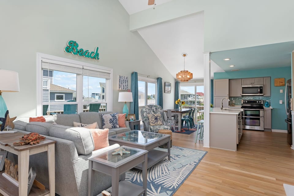 Great room with open concept floor plan, vaulted ceilings and beachy furnishings