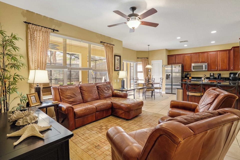 Spacious living area with leather seating and an open kitchen featuring stainless steel appliances.