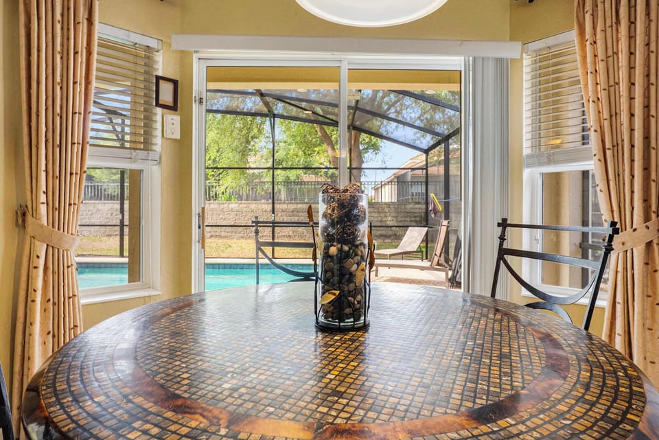Dining area with a mosaic table overlooking the screened pool and patio.