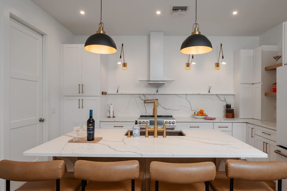 Modern kitchen island with marble countertops and leather bar stools