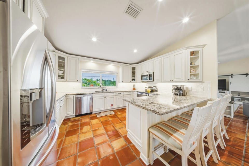 Bright and spacious open-concept kitchen overlooking the canal in this Marathon, Florida Keys vacation rental with private pool. Perfect for entertaining, the kitchen flows seamlessly into the dining area with stunning waterfront views.