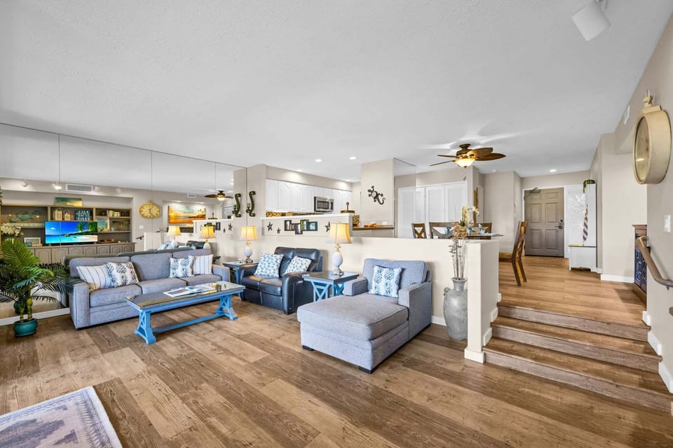 Spacious open living area with a unique step‑down design, comfortable seating, and warm wood floors throughout.