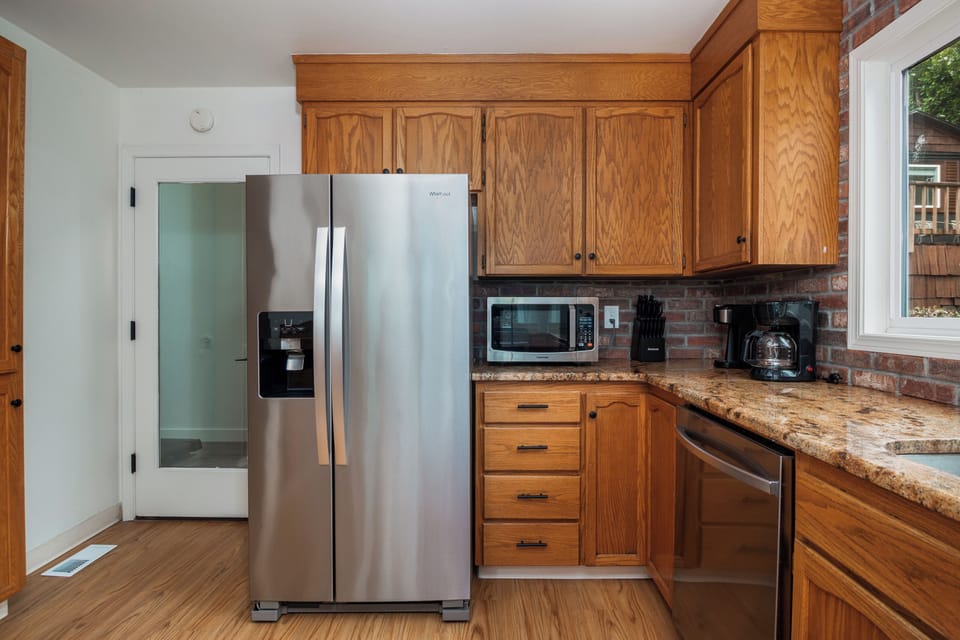 A fully-equipped kitchen awaits you with stainless steel appliances, warm oak cabinetry, granite countertops, and charming exposed brick accents. Everything you need to prepare home-cooked meals during your stay.