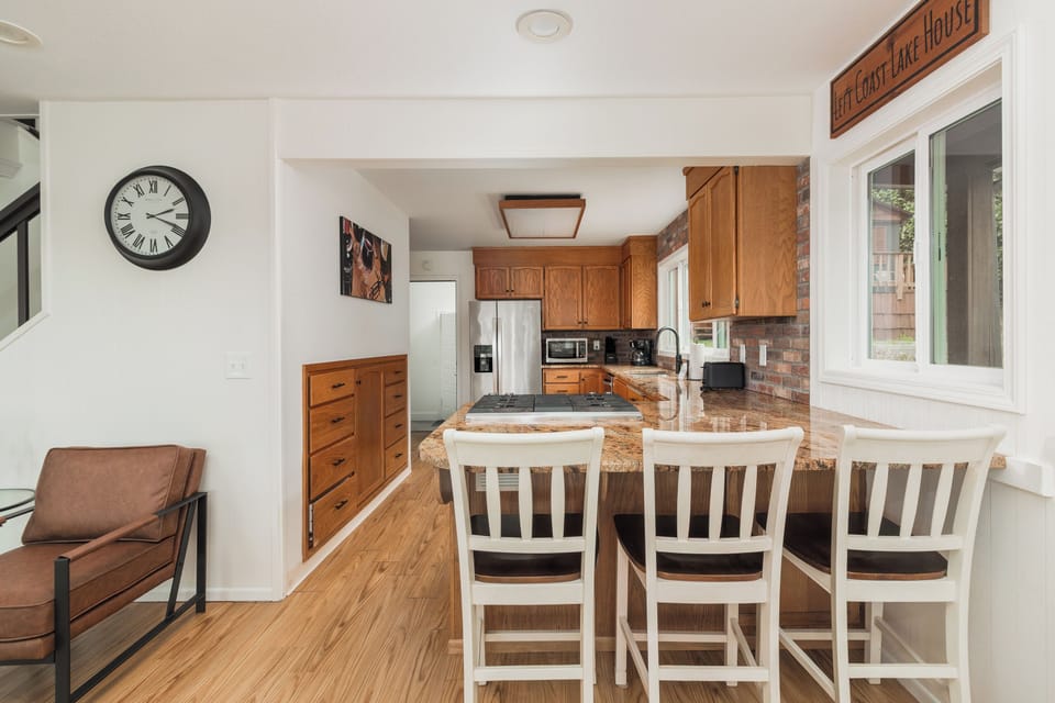 Enjoy morning coffee at the granite breakfast bar, where warm wood tones and updated appliances blend rustic charm with modern convenience in your open-plan kitchen.