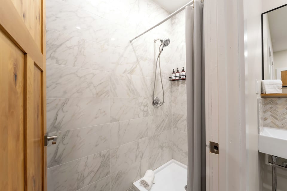 Step into your pristine marble-tiled shower, where sleek fixtures and premium amenities await to refresh you after a day of exploring.