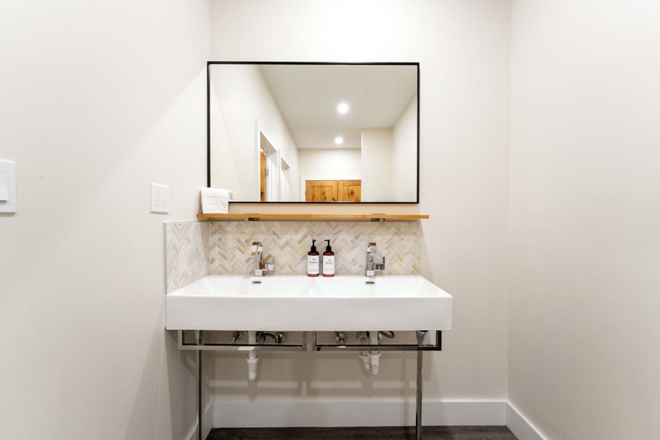 Refresh yourself at this modern double vanity featuring a chic herringbone backsplash, sleek fixtures, and premium toiletries—your morning routine just got an upgrade.
