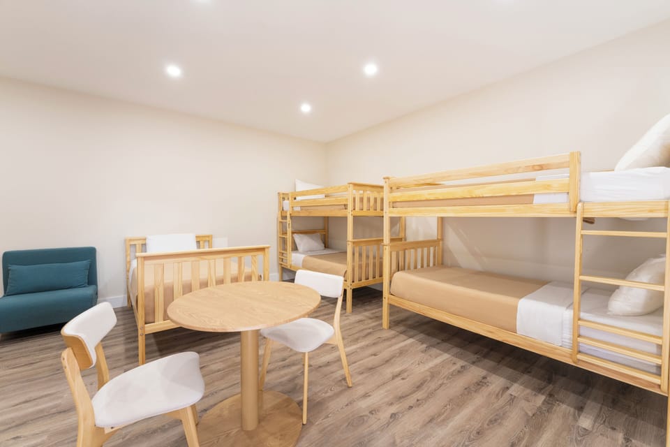 Ideal for families or groups, this spacious room features multiple bunk beds, a cozy seating area, and a welcoming dining spot for shared meals and memorable moments together.