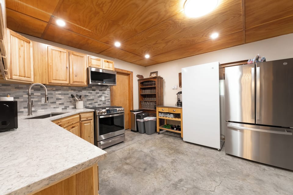Step into your fully-equipped kitchen, where warm wood tones meet modern stainless appliances. Prepare your favorite meals beneath a stunning wood-grain ceiling with abundant counter space at your fingertips.