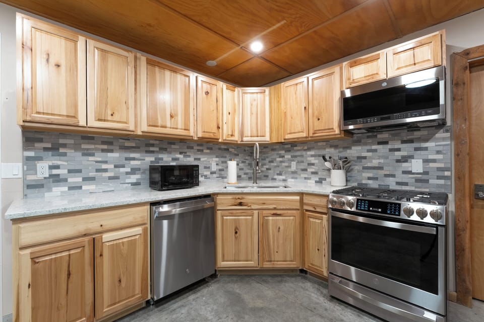 Your fully equipped kitchen features warm wood cabinetry, modern stainless appliances, and a stylish tile backsplash—everything you need to prepare favorite meals during your mountain retreat.