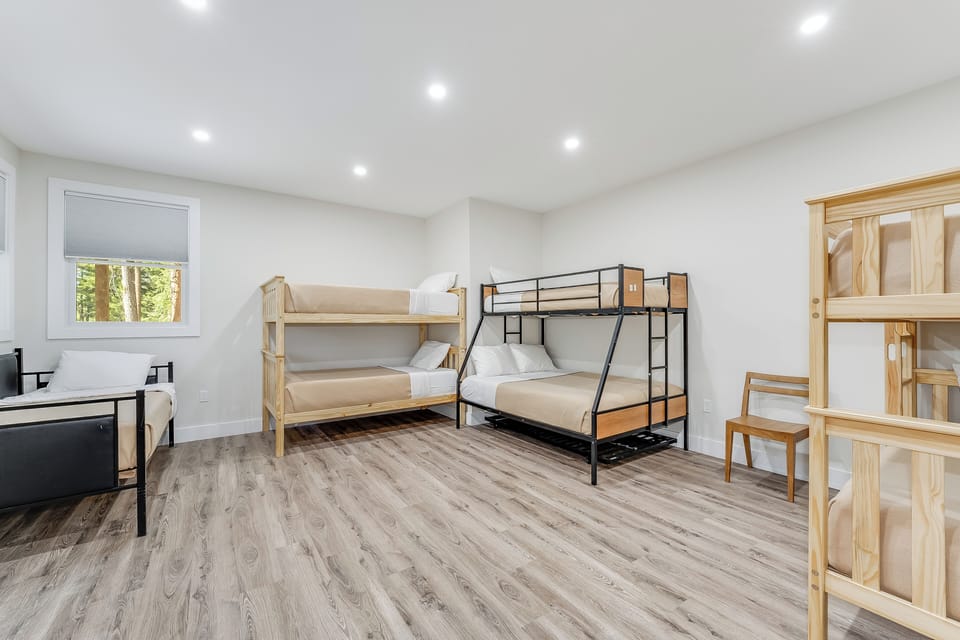 Spacious bedroom designed for families or groups, featuring multiple bunk beds with fresh linens, natural light from a peaceful garden view, and modern flooring for your comfort.