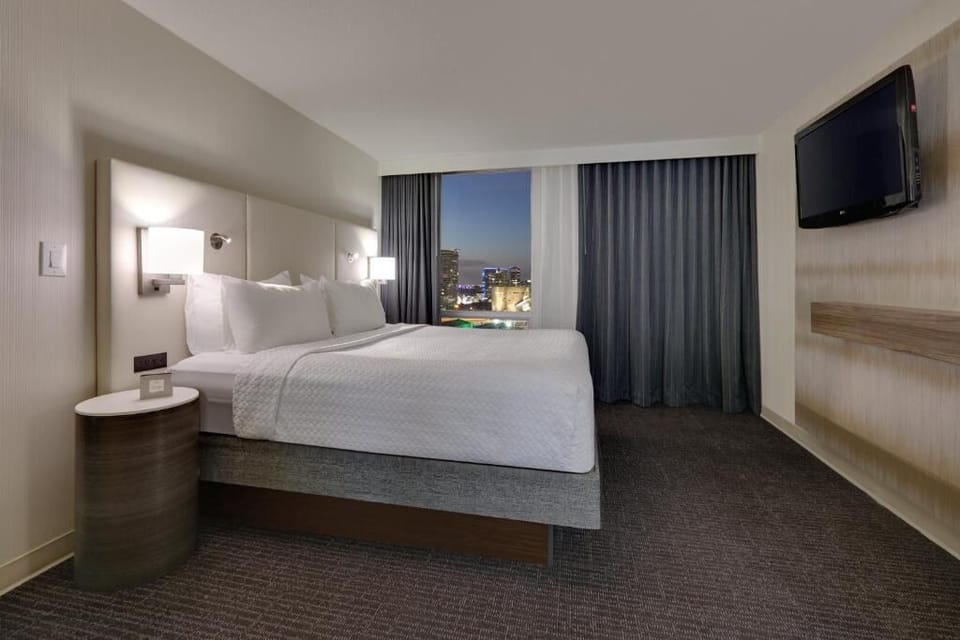 Drift off after sunset with skyline views beyond the curtains.