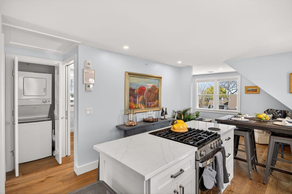 Your beautifully lit kitchen features white cabinetry, a spacious island with a built-in gas range, and all the conveniences you need to craft delicious meals during your stay.