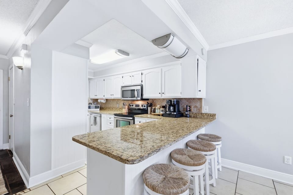 Bright kitchen with granite breakfast bar and seating for four