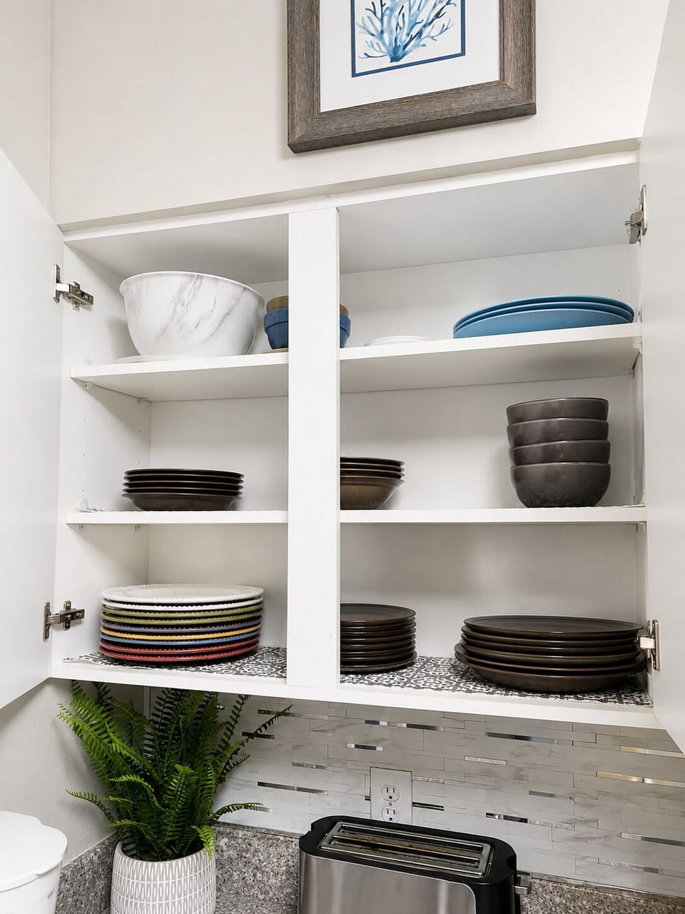 Well-stocked kitchen cabinet with stylish dishware and modern finishes
