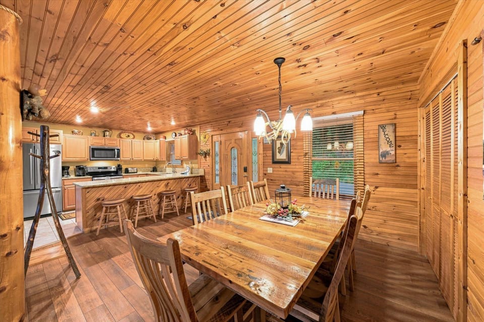 Rustic open dining area with large table, breakfast bar, and cozy cabin charm