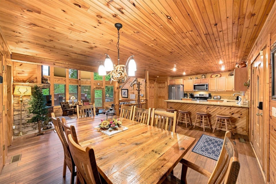 Rustic open-concept great room with fireplace, dining table, and breakfast bar