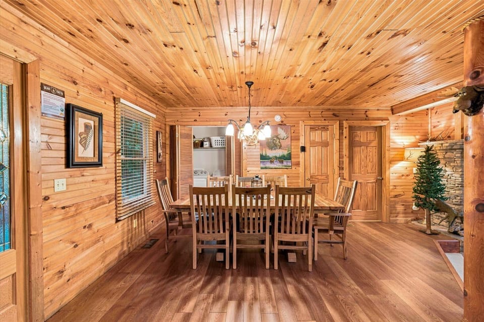 Warm wood-lined dining space with large table and cozy cabin charm