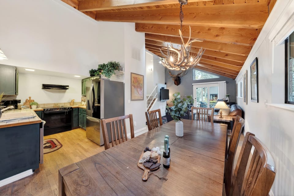Dining area with wood table, antler chandelier, and warm cabin charm.