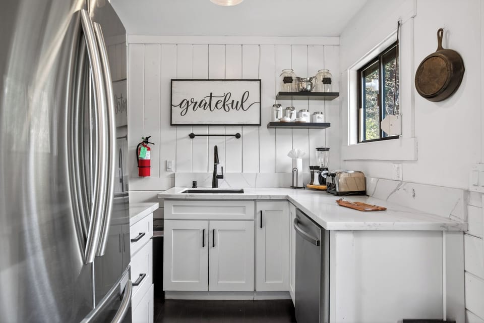 Bright and modern culinary space featuring white cabinetry and stainless steel accents.