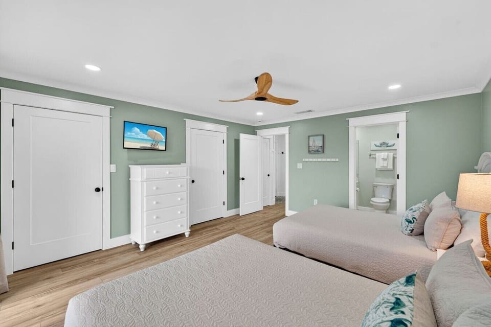 Large guest bedroom featuring two queen size beds and private balcony access.