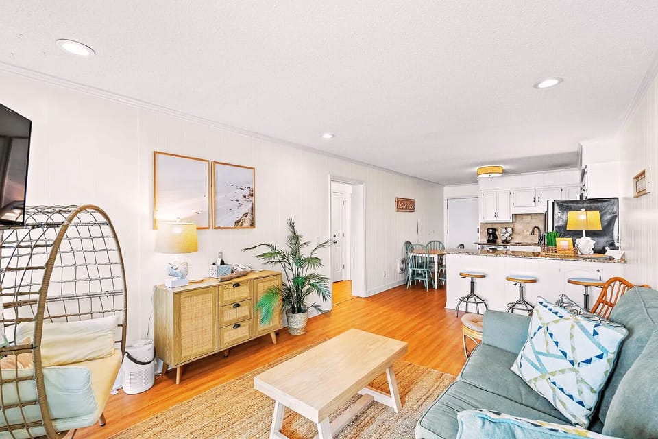 Bright open living space with kitchen bar, cozy seating, and beachy charm