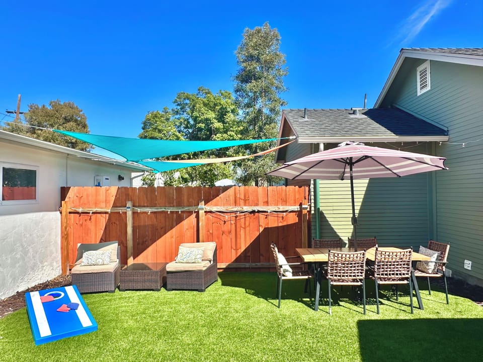 Private yard with cornhole, lounge chairs and shaded outdoor dining.