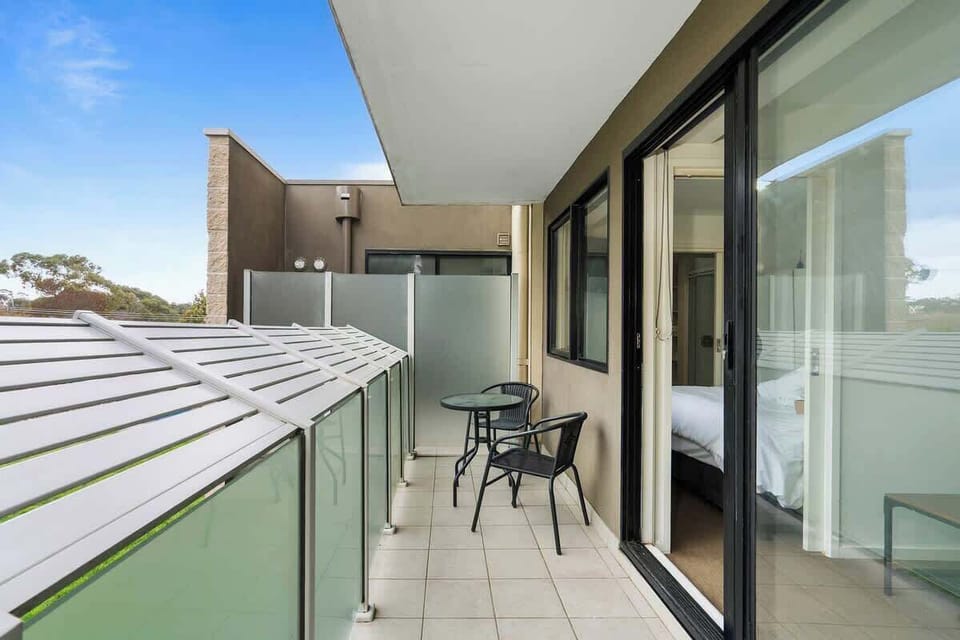 Private Sunlit Balcony A serene outdoor terrace featuring a compact cafe table and chairs. Wide sliding doors offer effortless indoor-outdoor flow straight from the bedroom, making it the perfect spot for your morning coffee.
