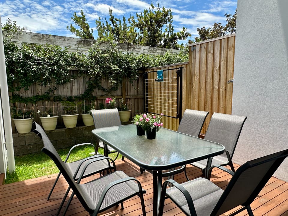 Private garden patio with outdoor dining and lush, leafy surrounds
