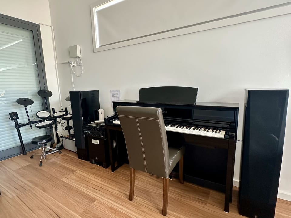 Private music room with piano, drum kit, and modern audio setup