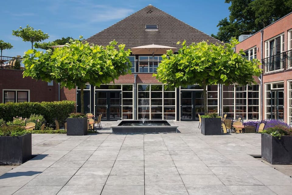 Arrive to a serene courtyard terrace framed by greenery.