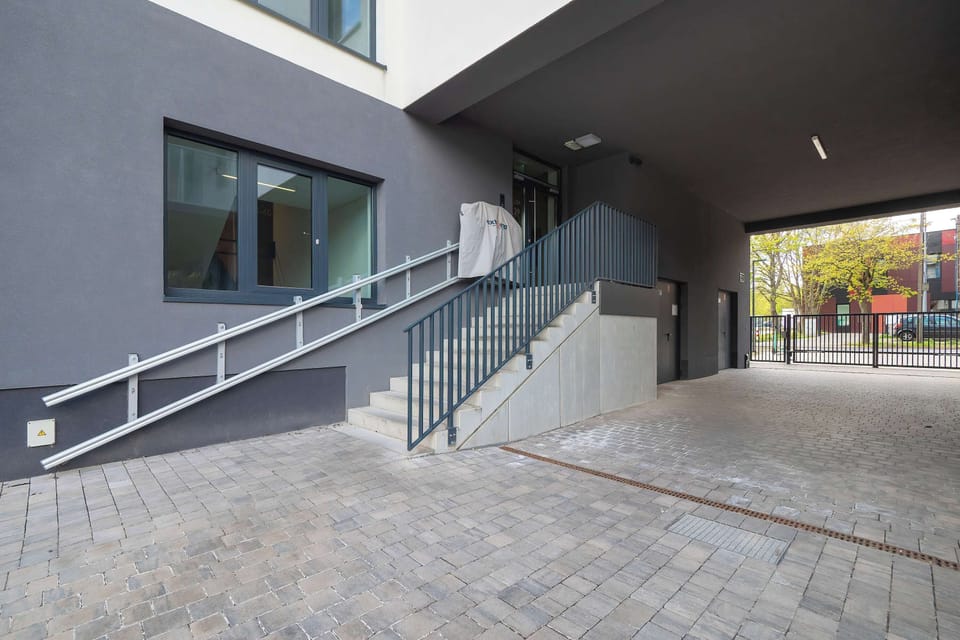 An exterior entrance area with stairs, a ramp, and a covered walkway leading into a building.