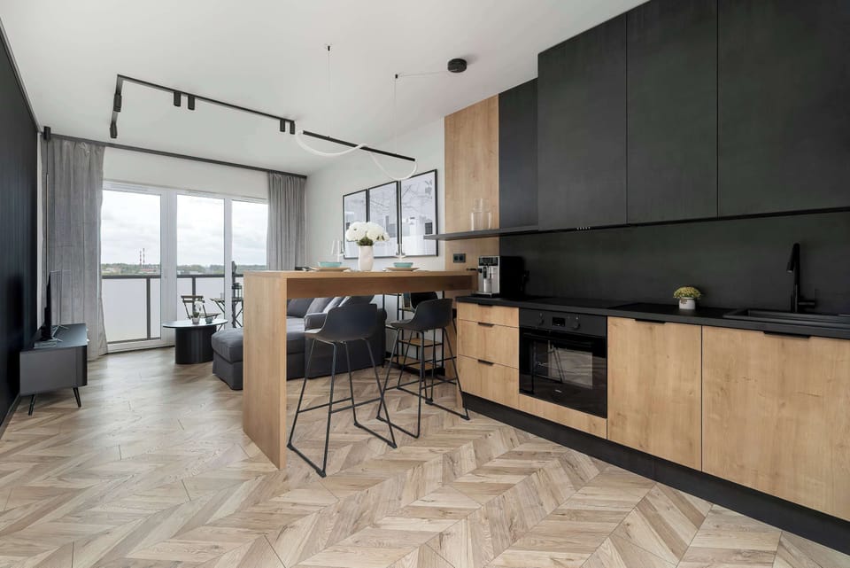 A sleek kitchen interior with black countertops, wooden cabinets, and bar stools.