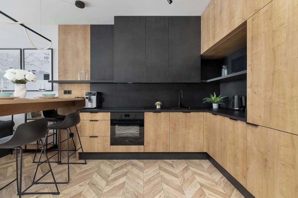 A contemporary kitchenette with black cabinetry, wooden finishes, and bar seating by the counter.