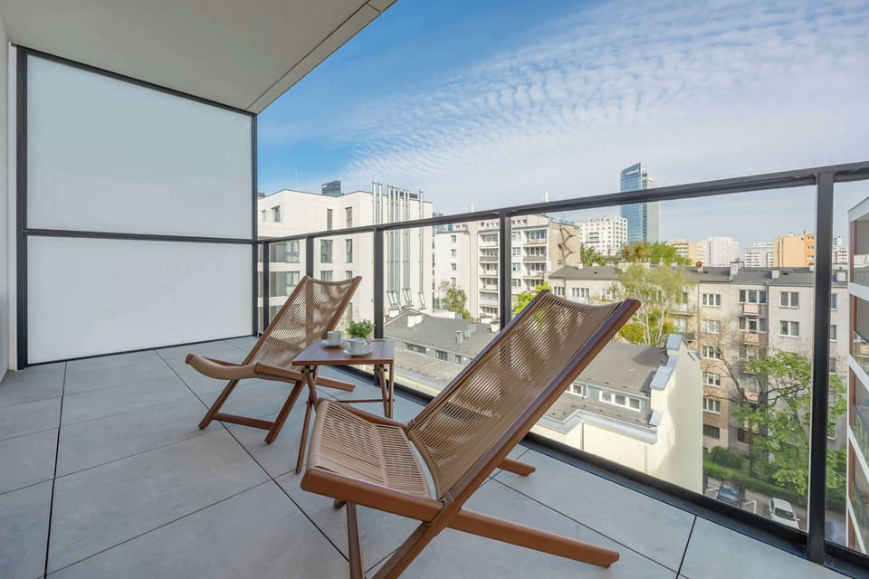 A balcony with wooden chairs overlooking a residential neighborhood.