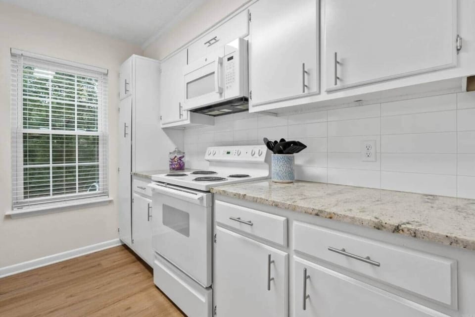 Kitchen includes stove, microwave, ninja foodie, blender, toaster, pots and pans, and some baking dishes.