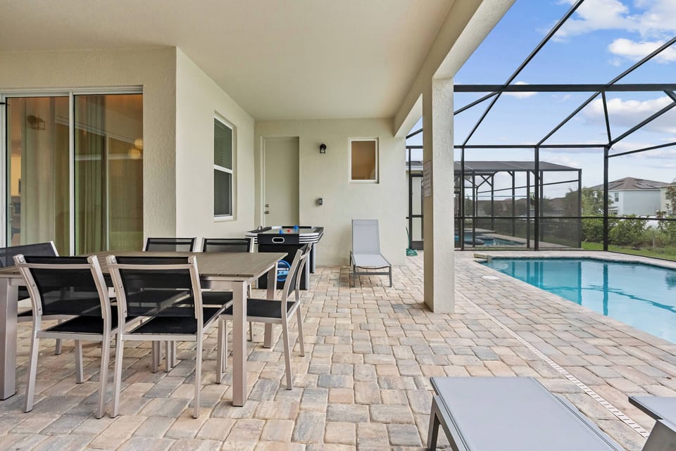Step outside to enjoy a sparkling pool surrounded by a screened patio, ideal for soaking up the sun. Relax on sleek lounge chairs as lush greenery peeks through, adding a refreshing touch of nature to your experience.