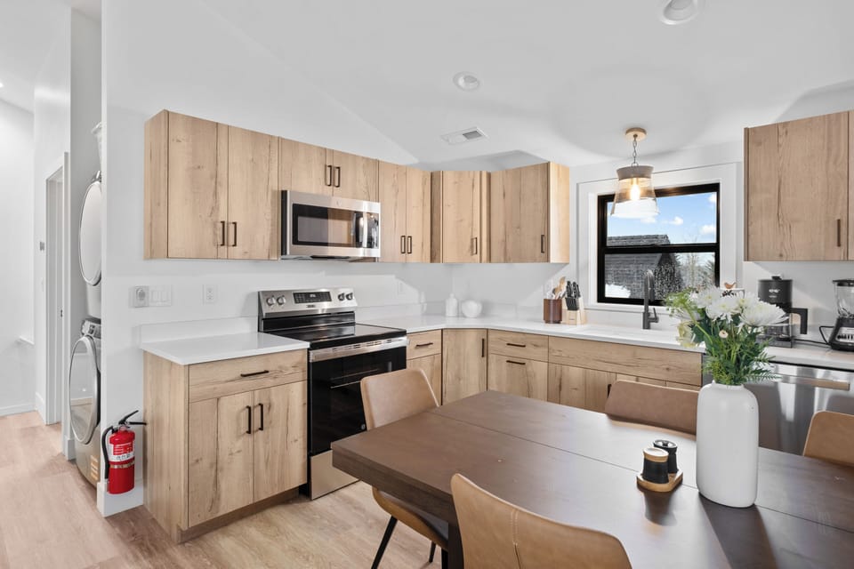 Bright modern kitchen with dining space, stainless appliances, and in-unit laundry