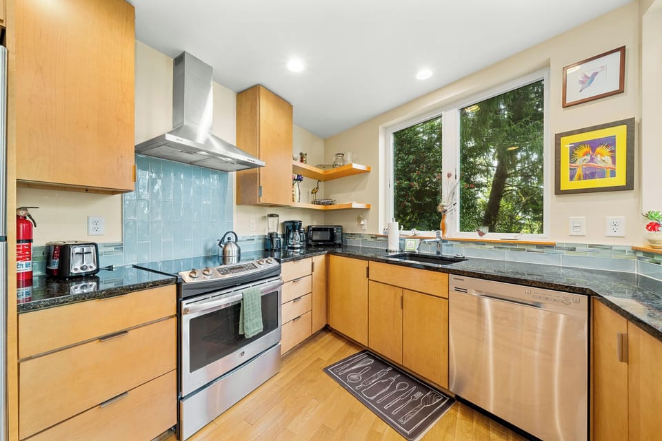 Your fully equipped kitchen invites you to create home-cooked meals with sleek appliances, ample counter space, and views of lush greenery through bright windows.