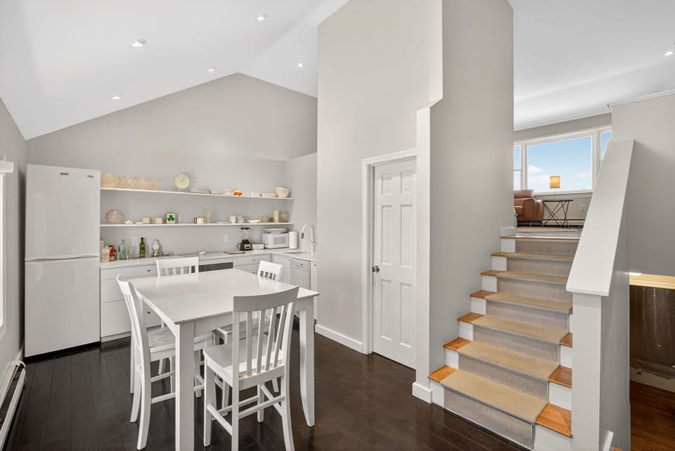 Bright, airy kitchen with open shelving and a cozy dining nook, leading upstairs to your private retreat. Natural light fills every corner, inviting you to relax and unwind.