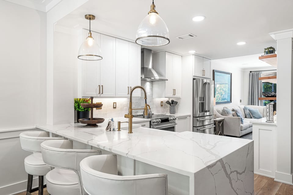 A modern kitchen with a large island and barstool seating. You can cook meals using the stainless steel appliances or sit at the counter for a quick snack.