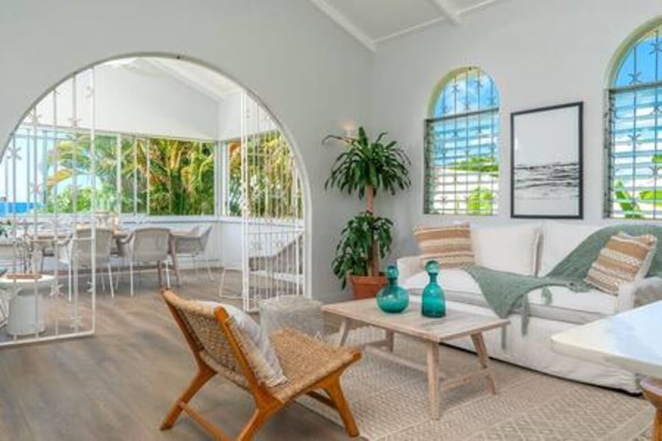 Open plan living room with flat screen TV, neutral decor and views out to sea.