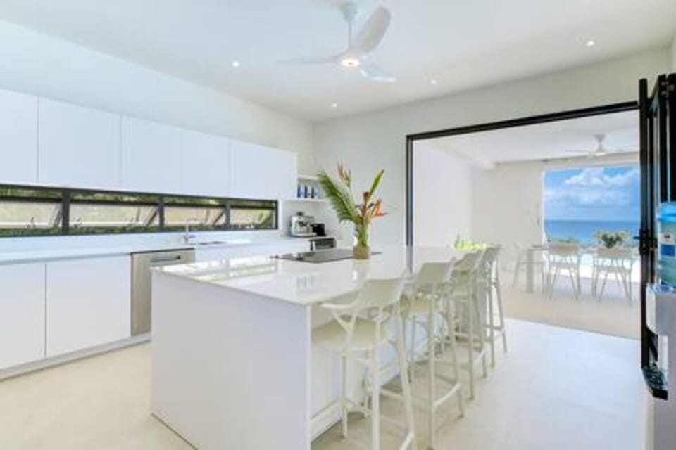 Modern and well appointed kitchen including a large breakfast bar, coffee maker, dishwasher, electric hob, kettle, oven, toaster and air conditioning.