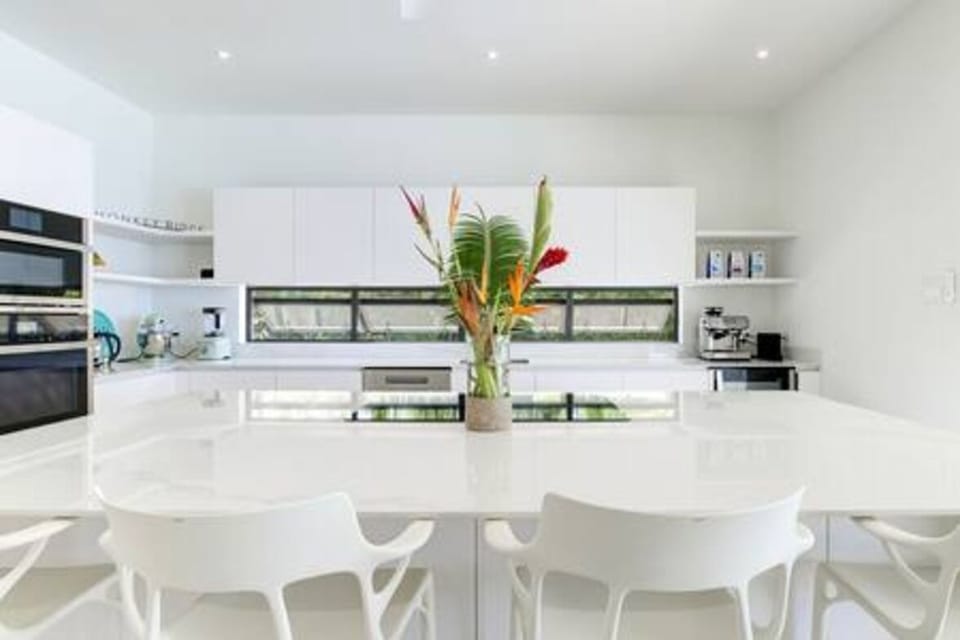 Modern and well appointed kitchen including a large breakfast bar, coffee maker, dishwasher, electric hob, kettle, oven, toaster and air conditioning.