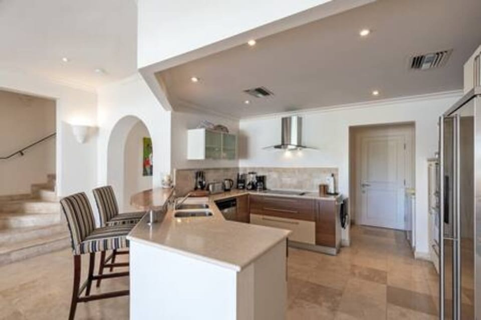 Modern open plan kitchen with breakfast bar, blender, coffee maker, dishwasher, tumble dryer and washing machine.